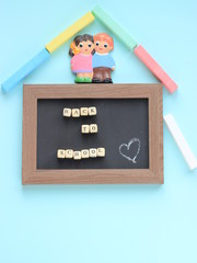 Calkboard with the inscription Back to school, colored chalks and a figure of a boy and a girl on a blue background. Letters inscription on wooden cubes. Chalk board and crayons depict the house.Card
