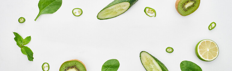 Fototapeta na wymiar panoramic shot of fresh cucumbers, kiwi, lime, peppers and greenery