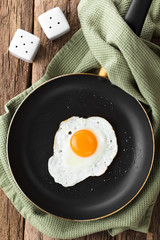 One fresh fried egg sunny side up in skillet, salt and pepper shaker on the side, photographed...