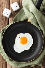 One fresh fried egg sunny side up in skillet, salt and pepper shaker on the side, photographed overhead (Selective Focus, Focus on the egg)