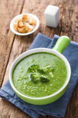 Fresh homemade cream of broccoli soup in bowl garnished with broccoli florets, fresh crispy croutons and salt shaker in the back (Selective Focus, Focus on the front of the first broccoli florets)