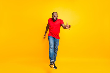 Fototapeta na wymiar Full length body size photo of angry furious yelling commanding black man wearing jeans denim screaming into camera while isolated with yellow vivid background
