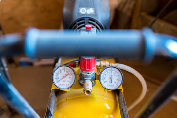 Dusty manometers on air compressor in a small carpentry work shop.