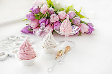 Pink homemade meringues on a white table with a bouquet of pink tulips. Gift set. Copy space