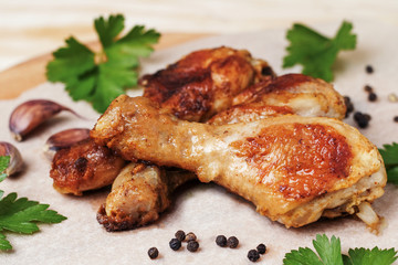 Roasted chicken legs with spices and herbs on a light background.