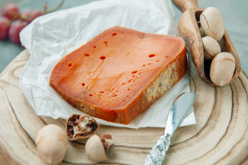 Delicatessen spicy cheeses. Red cheddar, on a beautiful textured wooden background with pecan nuts is a Savory snack for foodies. Selective focus