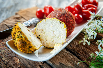 Delicacy round cheese Belper knoll with vegetables and aromatic herbs on a wooden table. Fresh farm products in Russia