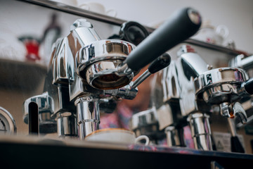 Coffee being brewed by the machine flowing through portafilter into the cup at cafe