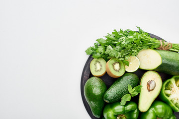 top view of avocados, peppers, kiwi, lime, zucchini and greenery on pizza skillet
