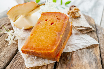 Delicatessen spicy cheeses of different varieties. Red cheddar, on a beautiful textured wooden...