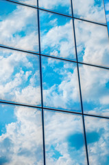 A skyscraper or modern building in a city with clouds and sunlight reflected in the Windows