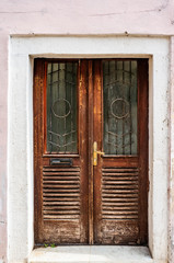 An old brown door in an old cracked stone wall. European street