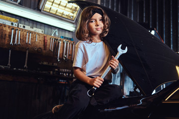Little pretty girls is dreaming to be at auto technicial, she is trying to fix broken car.
