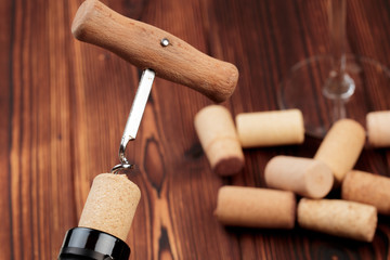 Fototapeta na wymiar Bottle of wine and cork and corkscrew on wooden table - image