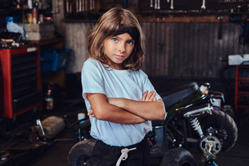Pensive little girl is posing for photographer crossed her hands at auto service.
