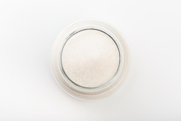 Sugar in  glass bowl on white background  top view