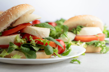 Sandwich with mozzarella, tomato and salad on the kitchen table.
