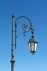Fototapeta na wymiar Old metal streetlight on blue sky background