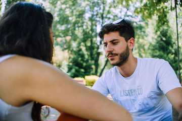 Casual couple resting in the park while sitting on the bench