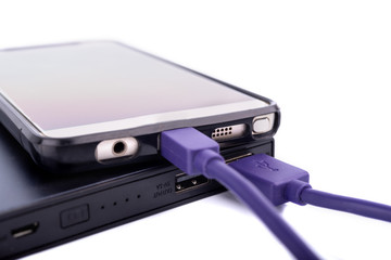 Close up of smartphone mobile charging by power bank with purple or violet usb cable isolated on white background.
