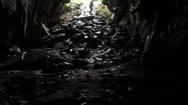 Traveler descends into cave. Stock footage. Traveler explores cave tunnel going down rope. Dangerous cave tunnels, slippery from damp and inspire fear of unknown darkness