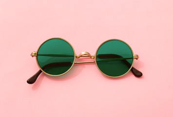 Vintage fashionable round green sunglasses on pink background