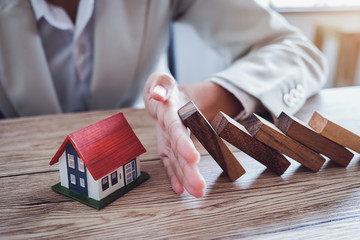 Protect the house from falling over the wooden blocks, Insurance and risk concept.