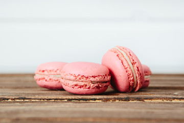 Sweet colorful French macaroon cookies dessert on brown wooden table over white wooden background