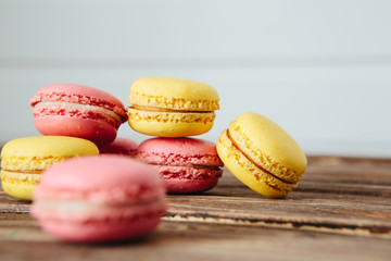 Sweet colorful French macaroon cookies dessert on brown wooden table over white wooden background