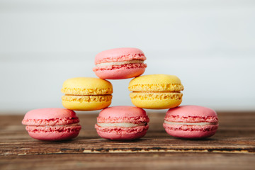 Sweet colorful French macaroon cookies dessert on brown wooden table over white wooden background