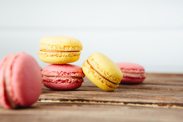 Sweet colorful French macaroon cookies dessert on brown wooden table over white wooden background
