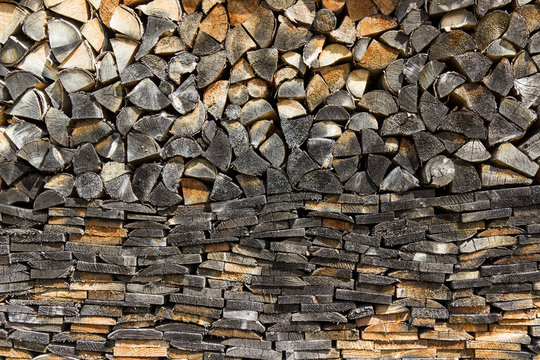 Background of dry chopped firewood laid in a woodpile. Close-up.