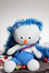  Сrocheted soft toy snowman in blue pants on table,close-up,space for text.Celebrating christmas - winter concept