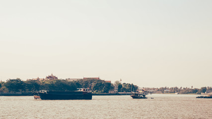 Sand transportation on river via big bucket boat, with Thai buddhist tample.