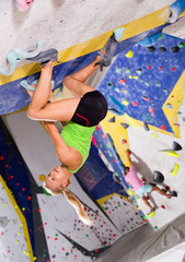 Young sporty woman training at bouldering gym without special climbing equipment