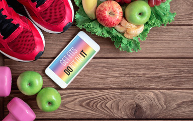 Fitness healthy lifestyle mockup smartphone concept. Get Fits Don't Quit quote on mobile phone with sport shoes, dumbbells and fruits. Mock up mobilephone for fitness healthy concept.