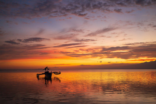 Coucher de Soleil éclairant un bateaux sur la plage de Paliton avec Cebu en arrière plan