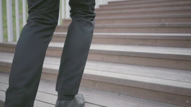 Legs of a stylish well-dressed businessman in expensive suit and shoes walking upstairs. Office lifestyle, business concept. The man in the suit walking outdoors. Climbing stairs.