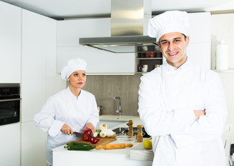 Male chef  in white uniform standing near workplace on kitchen