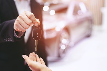 Car key, businessman handing over gives the car key to the other woman on car background. Leave a...