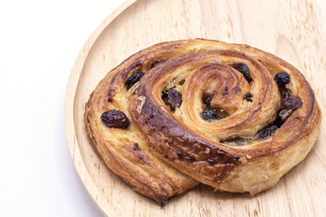 Raisin Danish pastry on wooden plate background.