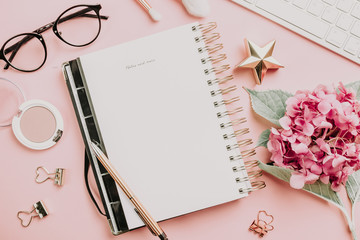 Female workspace with laptop, pink hydrangea, golden accessories, pink diary on pink background. - obrazy, fototapety, plakaty