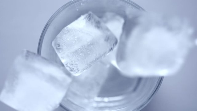 Throw ice cubes in empty glass. Icecubes falling down in cup