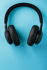 Fototapeta na wymiar Black bluetooth headphones on a blue background top view. In-Ear Headphones for DJs