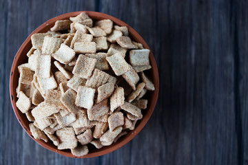 Whole grain cinnamon flakes in a brown bowl. Breakfast cereals. The concept of a quick and healthy breakfast. Top view.
