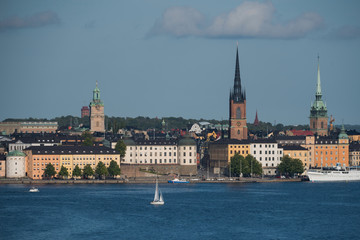Fototapeta premium Stockholm buildings at the bay Riddarfjärden between the district Södermalm, Kunsholmen, Gamla Stan and Riddarholmen at sunset with a low sun and fogg torning up in the archipelago
