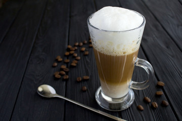 Coffee latte in the glass on the black wooden background. Copy space. Closeup.