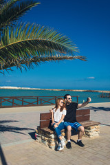 young couple sitting and  taking a selfie picture on beach