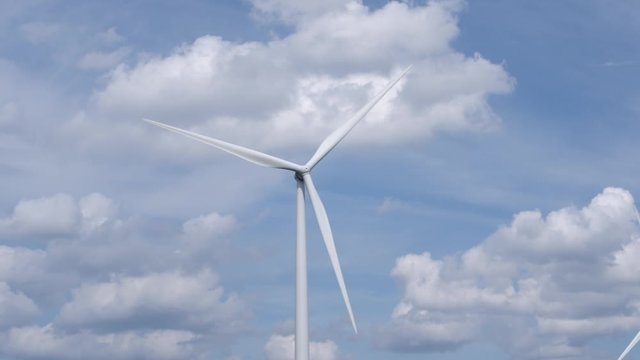 Wind turbine spins around for generating energy with clouds