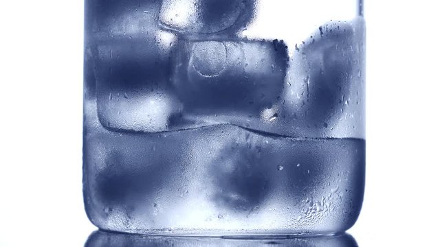 Ice cubes melting in drinking glass. Nobody. Blue tone
